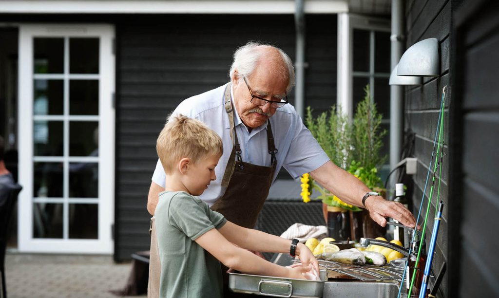Bestefar koker fisk på utekjøkkenet sammen med barnebarnet